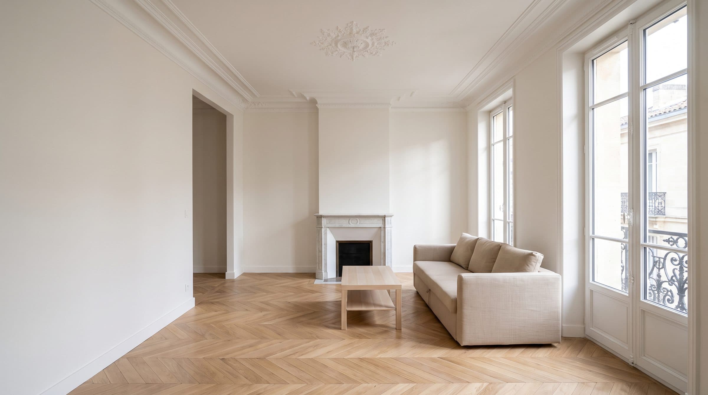 Le même séjour après rénovation : parquet en point de Hongrie, murs lisses, cheminée et moulures conservées